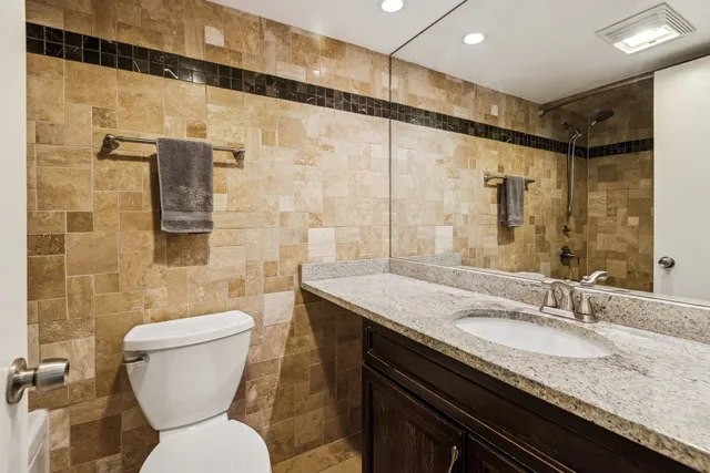 a bathroom with a granite countertop sink toilet and shower