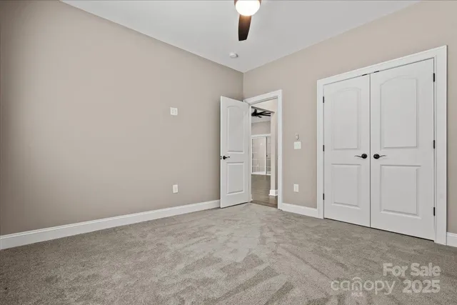 a view of an empty room and chandelier fan