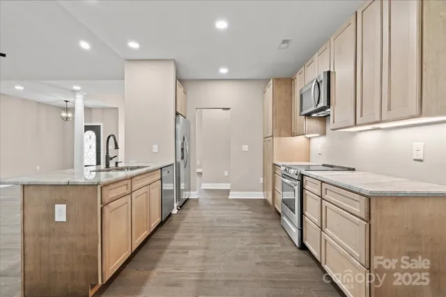 a large kitchen with stainless steel appliances granite countertop a lot of counter space and a sink