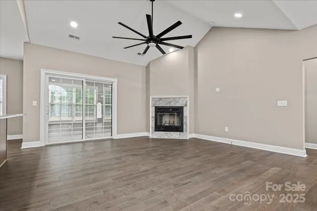 a view of a livingroom with a ceiling fan a fireplace and wooden floor