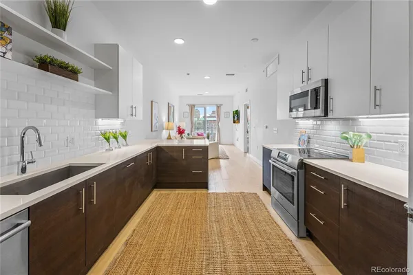 a kitchen with stainless steel appliances a sink dishwasher a stove top oven a refrigerator with wooden cabinets and floor