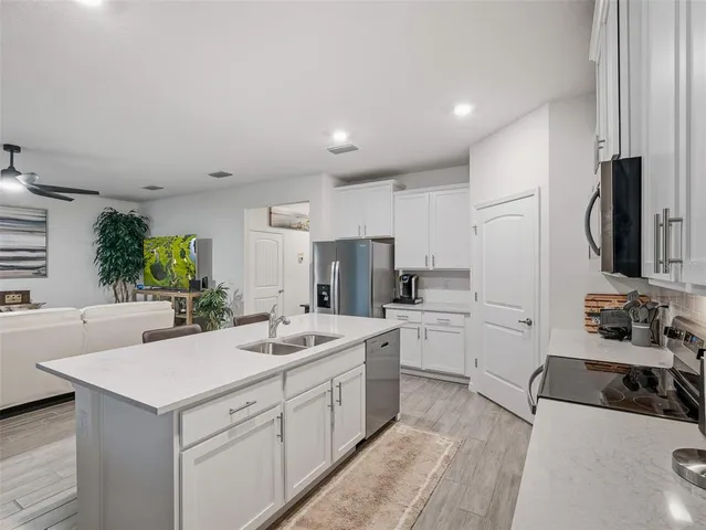 a kitchen with stainless steel appliances a stove a sink a microwave a refrigerator and white cabinets