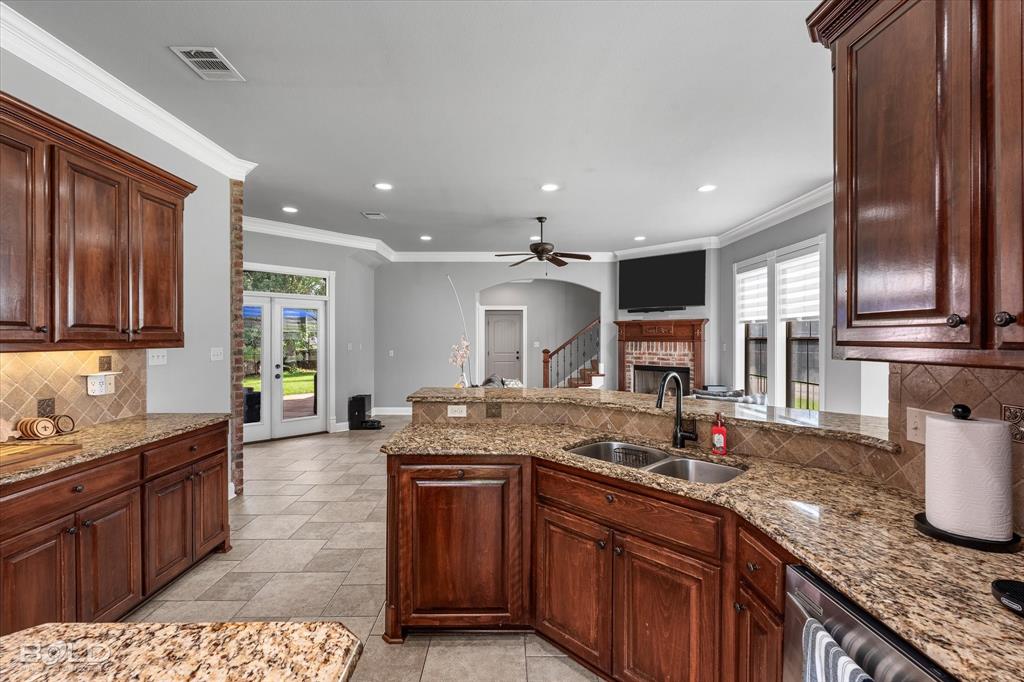 2220 Forest Hills Boulevard Haughton, LA 71037 - Photo 18 of 40 Kitchen featuring rich wood cabinetry, granite countertops, a double basin sink with a gooseneck faucet, and tile backsplash