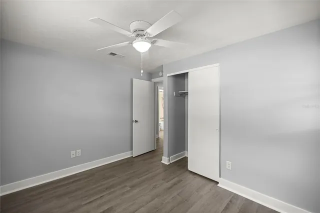 an empty room with wooden floor and fan
