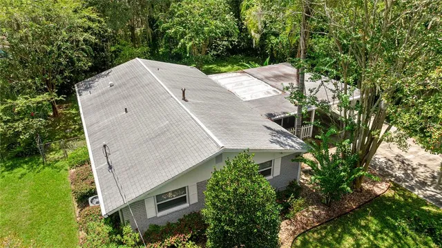 an aerial view of a house with a yard and large trees