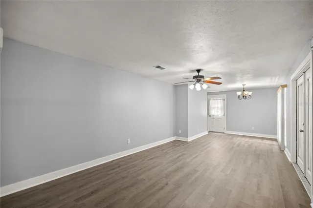 an empty room with wooden floor ceiling fan and window