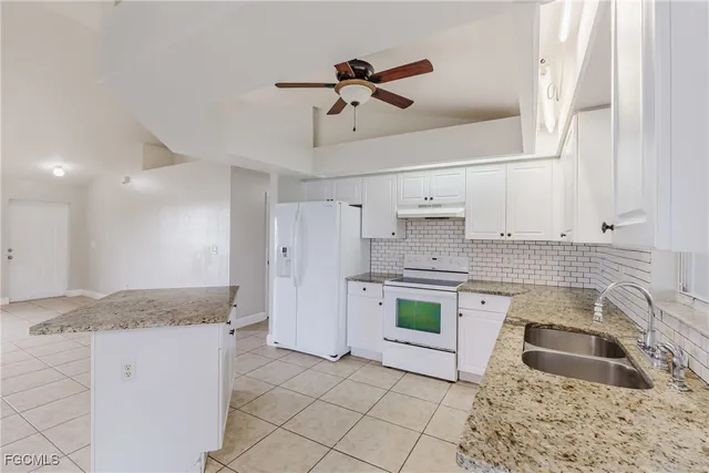 a kitchen with granite countertop a sink stove and refrigerator