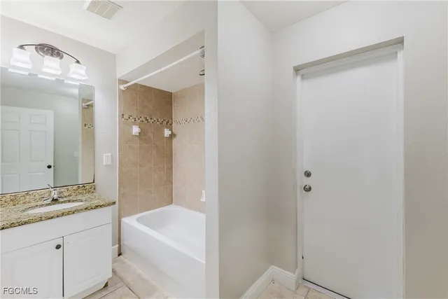a bathroom with a granite countertop sink a mirror and a bathtub
