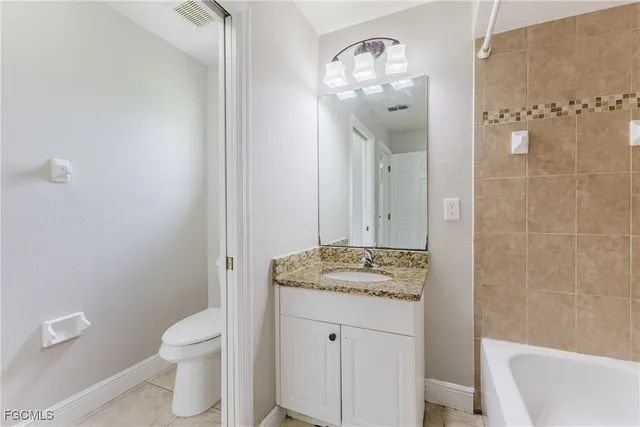 a bathroom with a granite countertop sink a toilet and shower