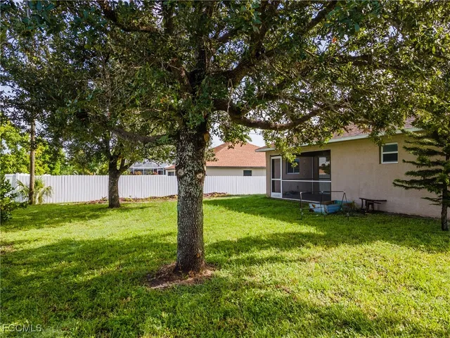 a backyard of a house with plants and large tree