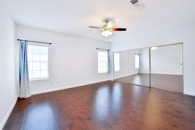 an empty room with wooden floor and windows