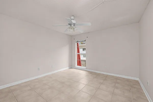 an empty room with chandelier fan and windows