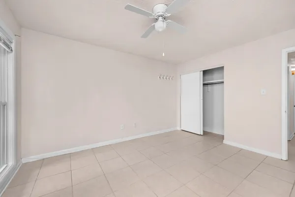 an empty room with a ceiling fan and a window