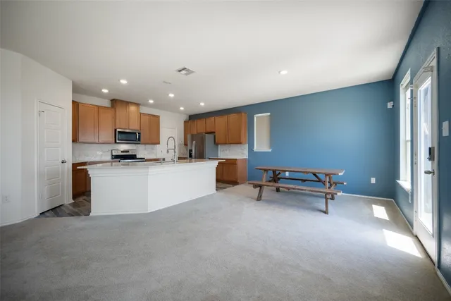 a kitchen with stainless steel appliances granite countertop a stove top oven a sink and a refrigerator