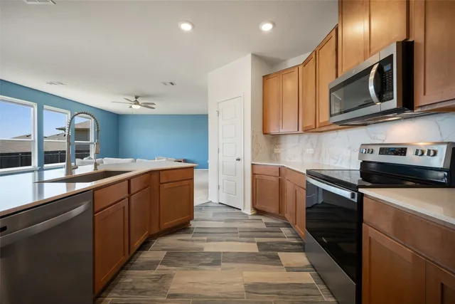 a large kitchen with stainless steel appliances wooden cabinets and a stove top oven