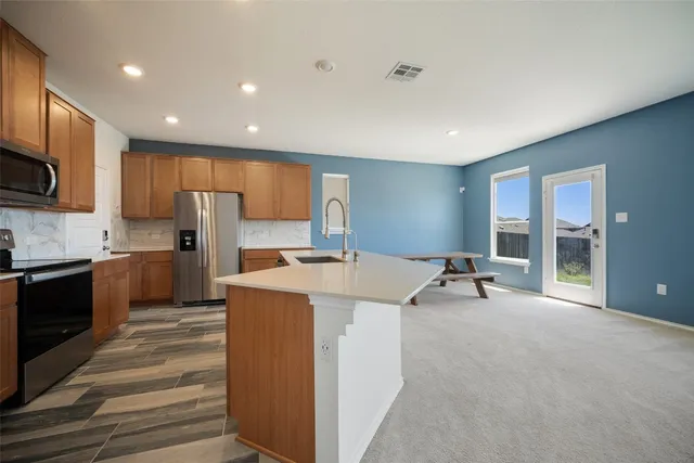 a large white kitchen with kitchen island a sink a stove and a refrigerator