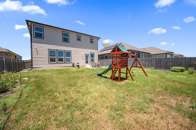 a backyard of a house with childrens swings and slides