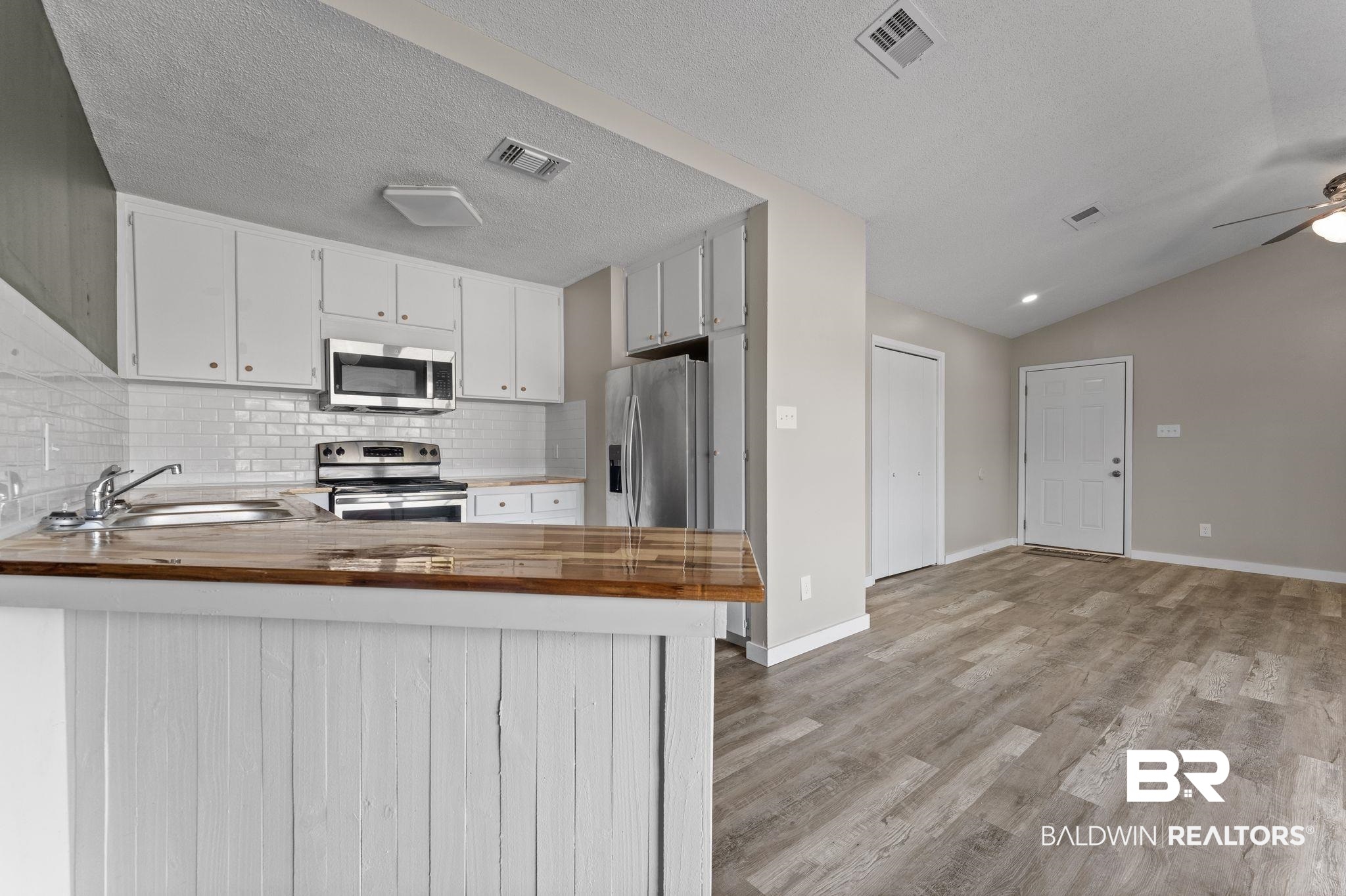 128 West Satsuma Avenue, Unit 128 Foley, AL 36535 - Photo 9 of 41 Kitchen with wooden counters, a peninsula, white cabinets, stainless steel appliances, and ceiling fan