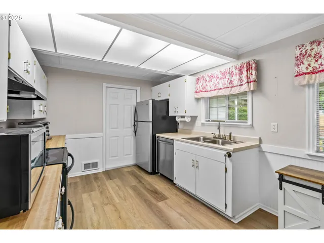 a kitchen with a sink cabinets stainless steel appliances and a window
