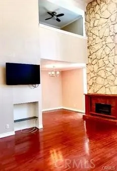 a view of an empty room with wooden floor and a fireplace
