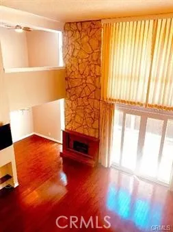 a view of an empty room with a window and hardwood floor