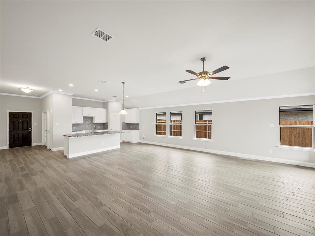 302 Pennington Road Josephine, TX 75173 - Photo 10 of 24 a view of an empty room with wooden floor and a kitchen