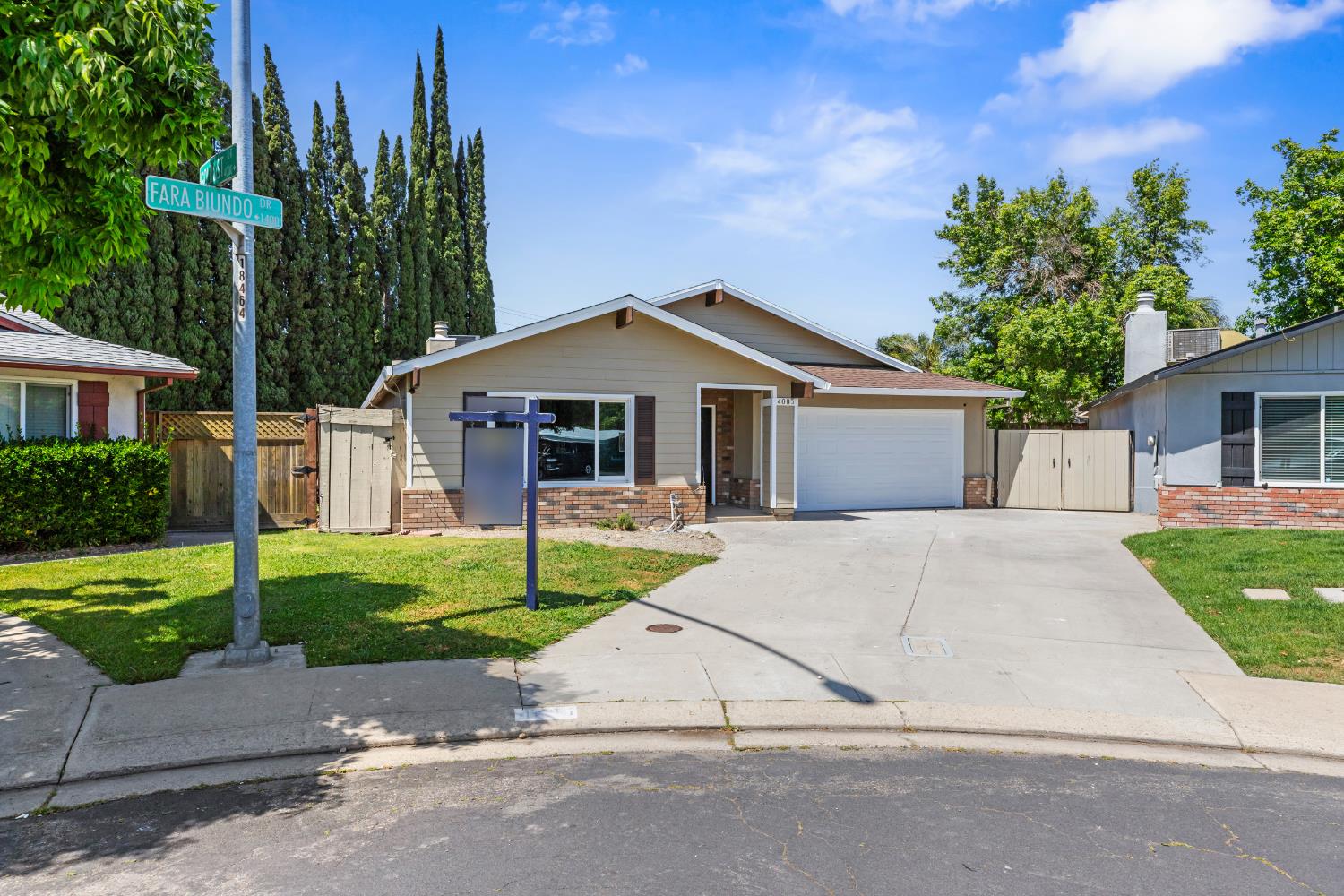 a white house with a small yard and large trees with wooden fence