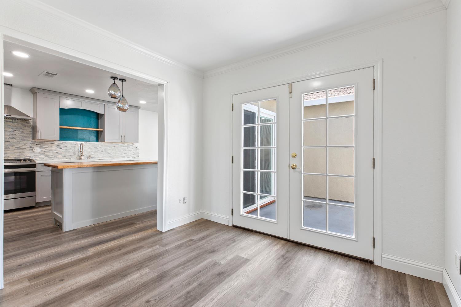 4005 Goldust Drive Modesto, CA 95355 - Photo 12 of 36 an empty room with wooden floor a kitchen view and windows