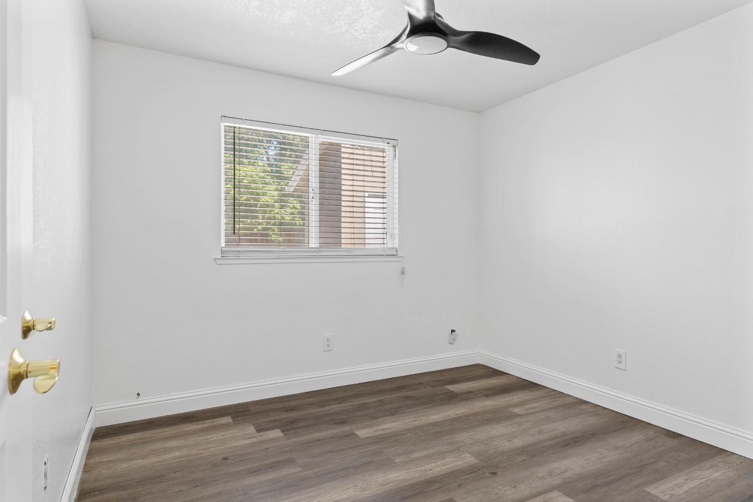 4005 Goldust Drive Modesto, CA 95355 - Photo 20 of 36 an empty room with wooden floor a ceiling fan and windows