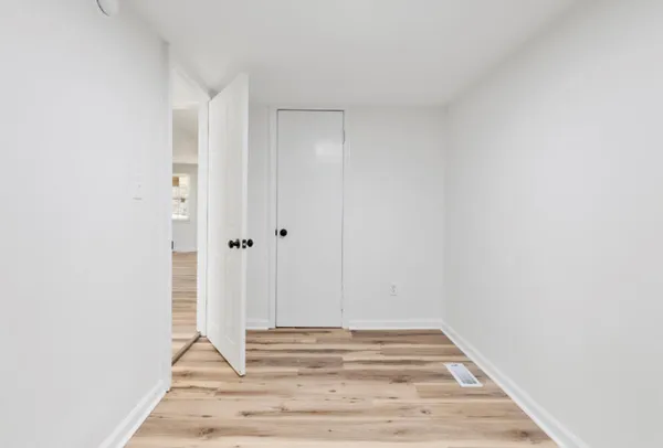 an empty room with wooden floor and windows
