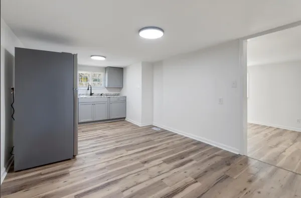 a view of empty room with wooden floor and fan