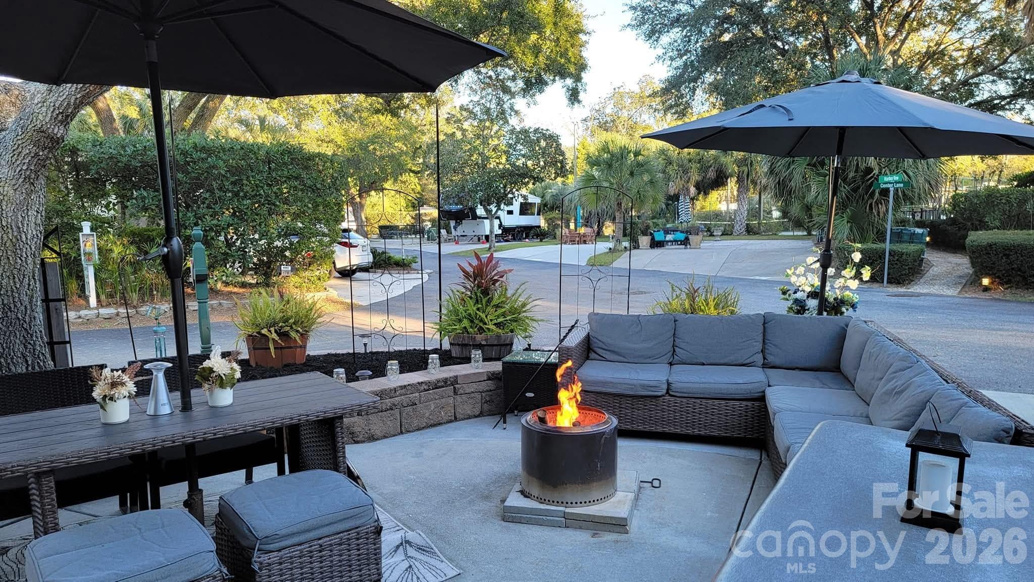 a view of a patio with couches table and chairs under an umbrella with a small yard