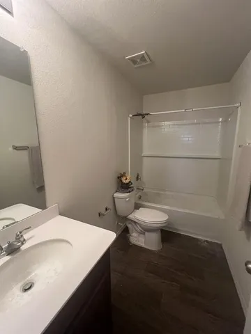 a bathroom with a granite countertop toilet a sink and a mirror