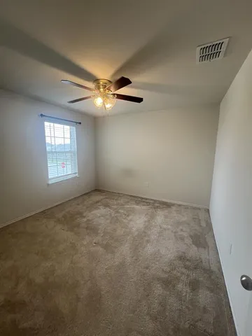 en empty room with windows and ceiling fan