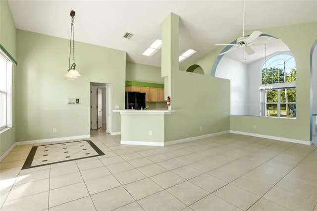 an empty room with chandelier fan and windows