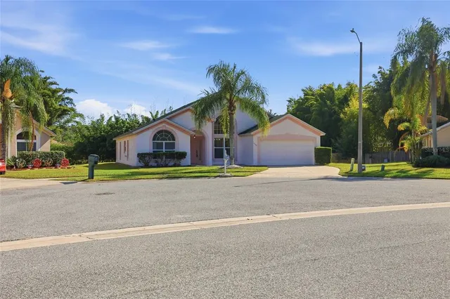 a view of a house with a yard and palm trees