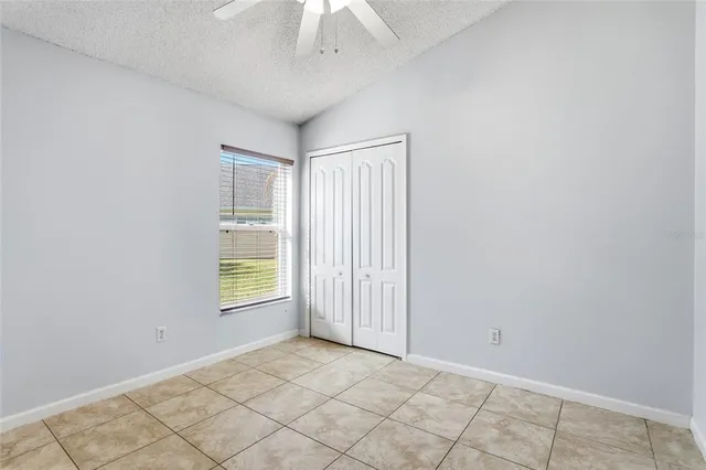 an empty room with a chandelier fan and windows