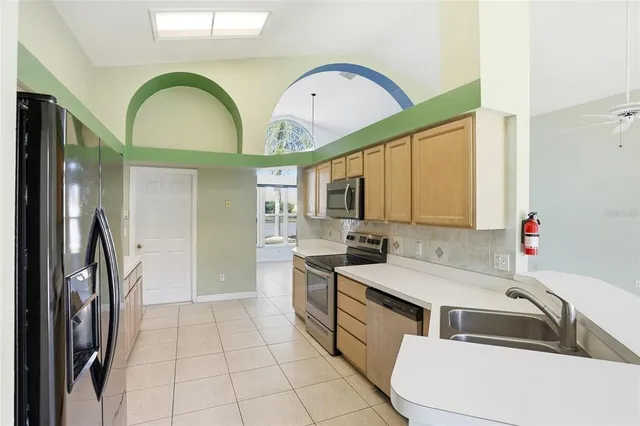 a kitchen with a sink a counter top space stainless steel appliances cabinets and a large window