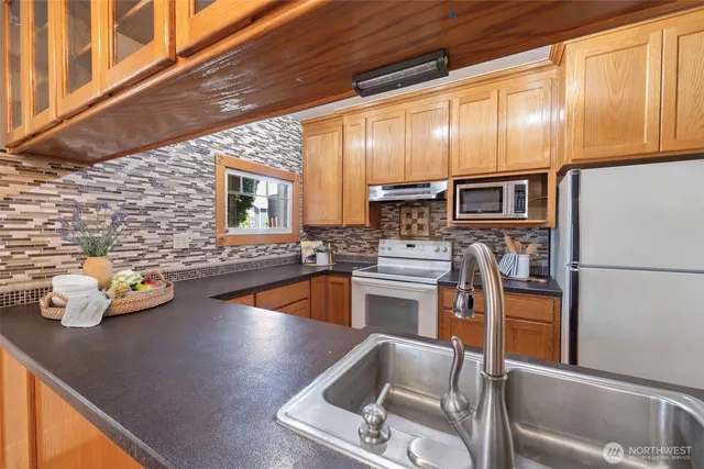 a kitchen with stainless steel appliances wooden cabinets a stove top oven a sink and dishwasher
