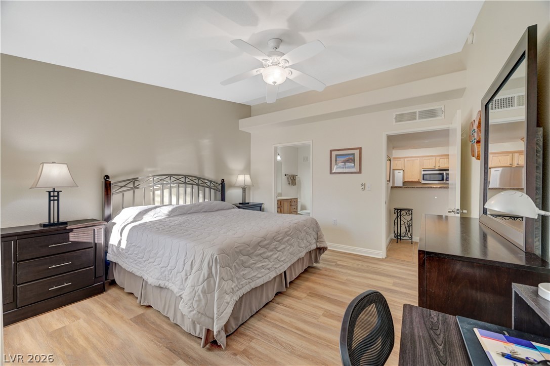 7885 West Flamingo Road, Unit 1071 Las Vegas, NV 89147 - Photo 14 of 28 Well-lit primary bedroom featuring durable wood flooring and an integrated ceiling fan for comfort.