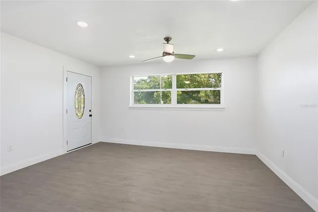 an empty room with windows and ceiling fan