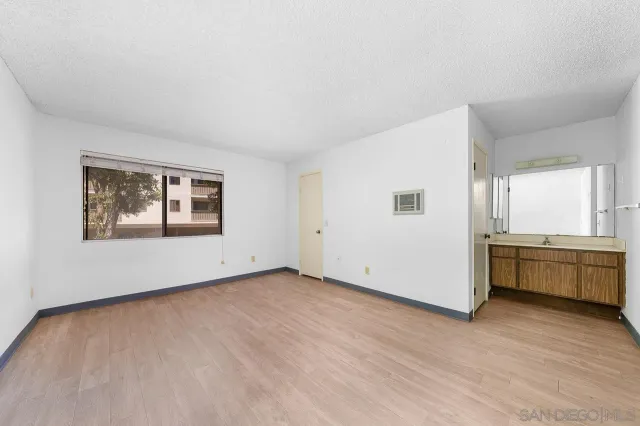 a view of an empty room with window and wooden floor