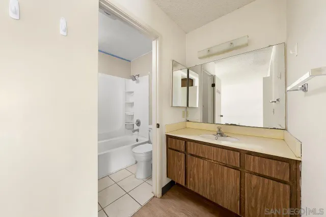 a bathroom with a granite countertop sink toilet mirror and bathtub