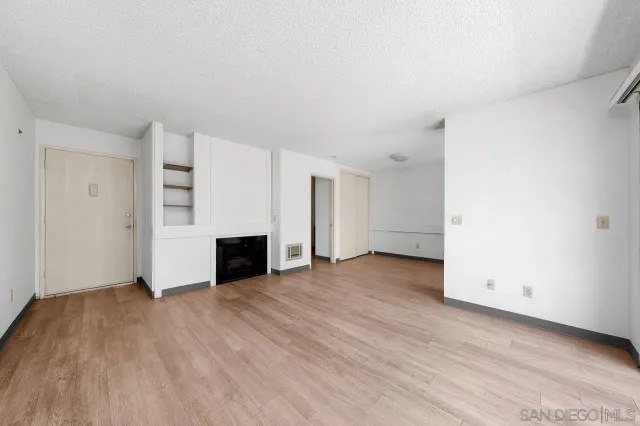 an empty room with wooden floor and fireplace