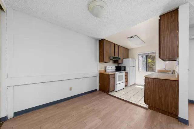 a kitchen with granite countertop a refrigerator stove top oven and sink