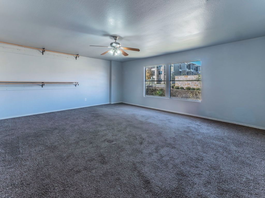 924 Satellite View Round Rock, TX 78665 - Photo 29 of 30 Loft area with a textured ceiling, dark colored carpet, and a ceiling fan