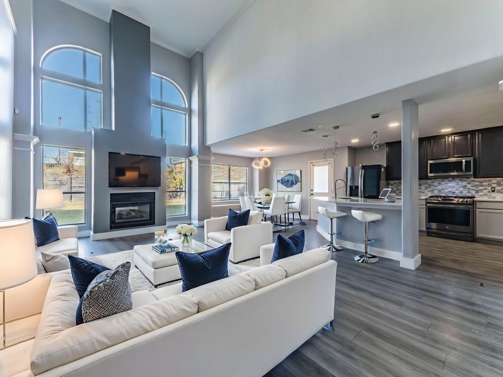924 Satellite View Round Rock, TX 78665 - Photo 5 of 30 VIRTUALLY STAGED Living room featuring ornamental molding, dark wood-type flooring, a high ceiling, a glass covered fireplace, and decorative columns