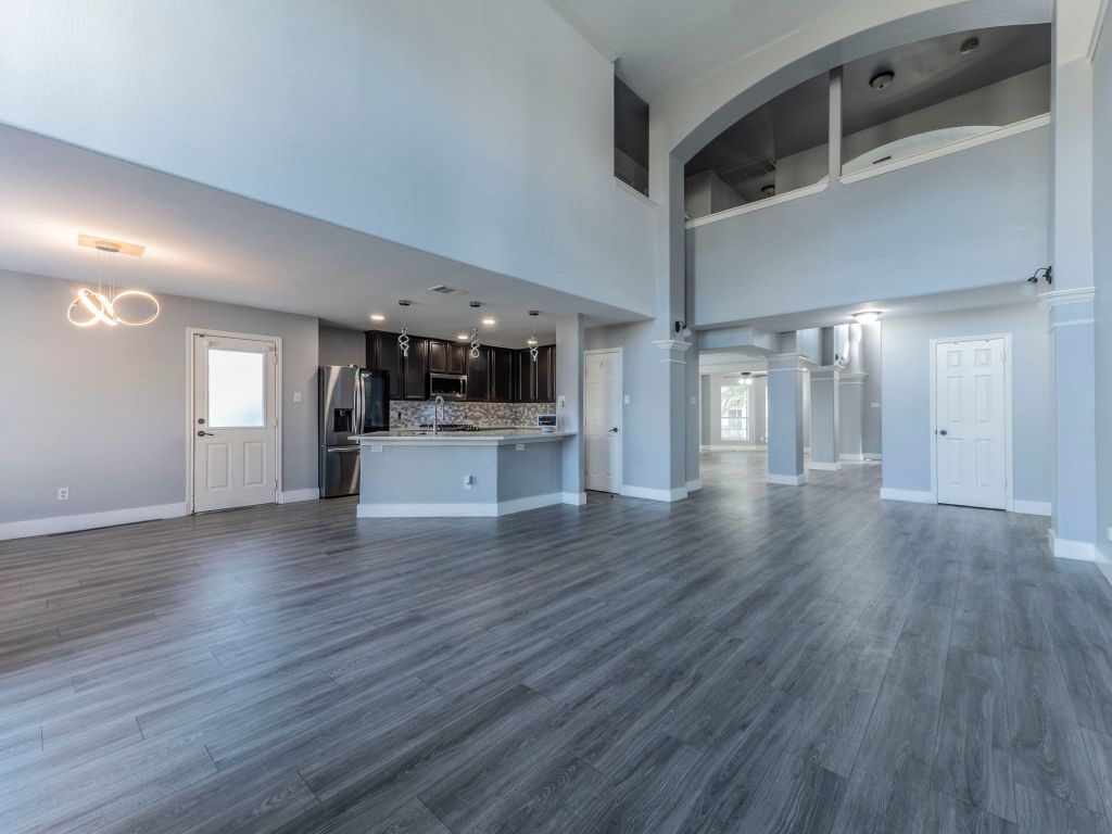 924 Satellite View Round Rock, TX 78665 - Photo 8 of 30 Unfurnished living room with grey lvp finished floors, and a high ceiling
