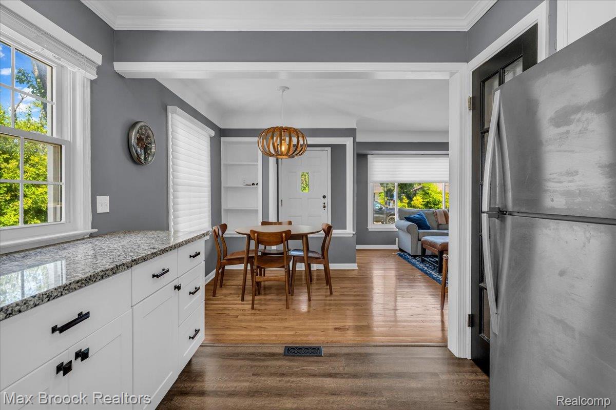 3711 Normandy Road Royal Oak, MI 48073 - Photo 12 of 40 Kitchen featuring freestanding refrigerator, white cabinets, light stone counters, hanging light fixtures, and dark wood finished floors