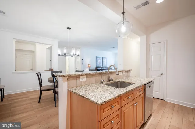 a kitchen with granite countertop kitchen island stainless steel appliances sink cabinets and wooden floor